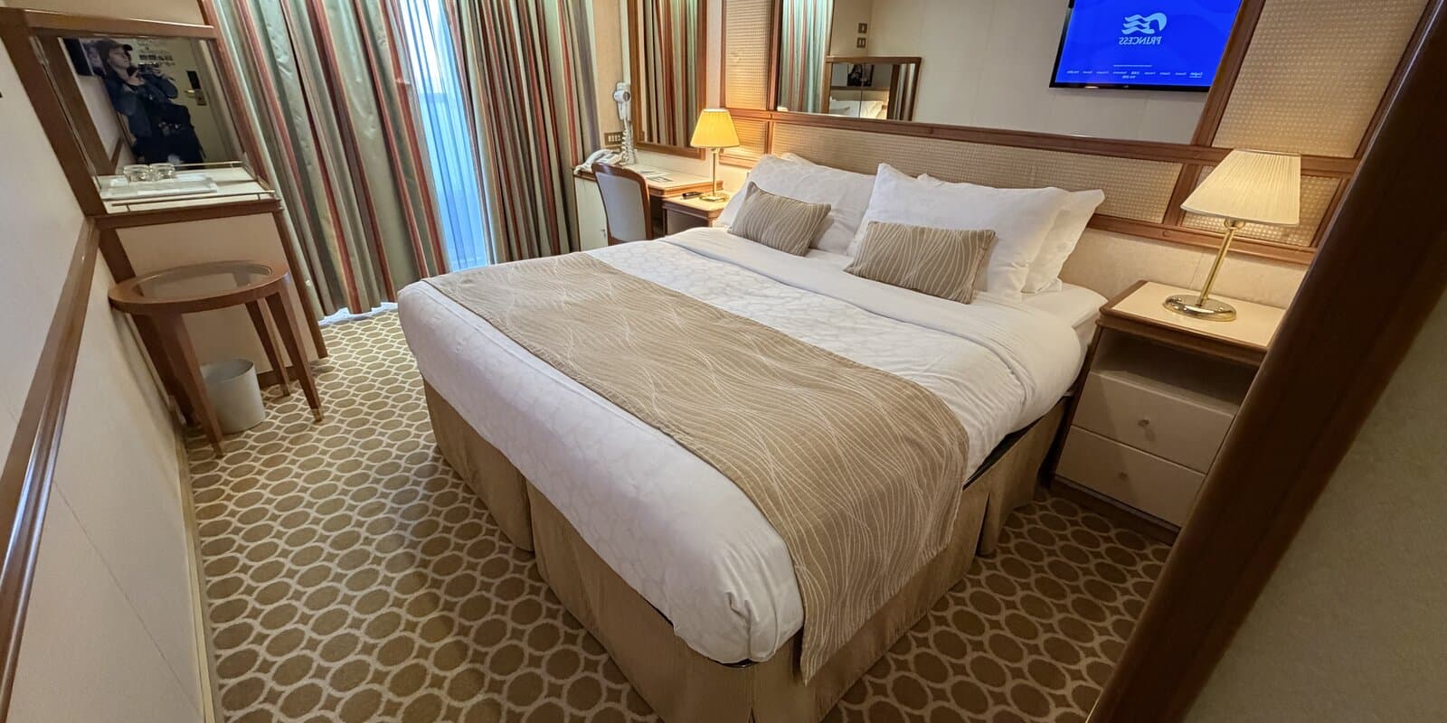 Interior of a Ruby Princess cruise stateroom with bed, desk, and closet