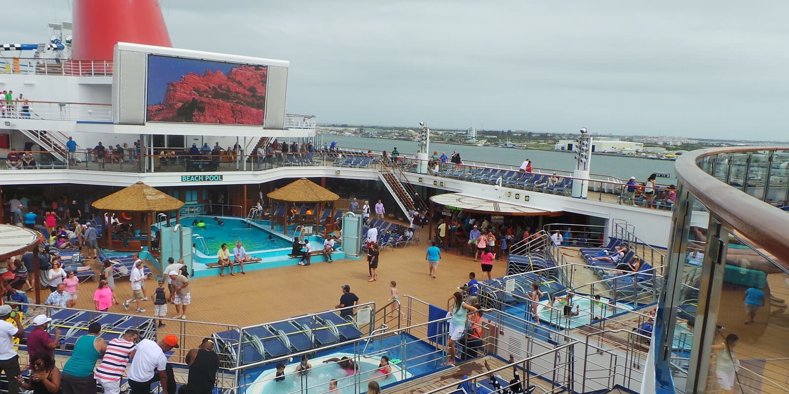 Overhead view of Carnival Sunshine's beach pool and lido deck with guests on a sunny sea day