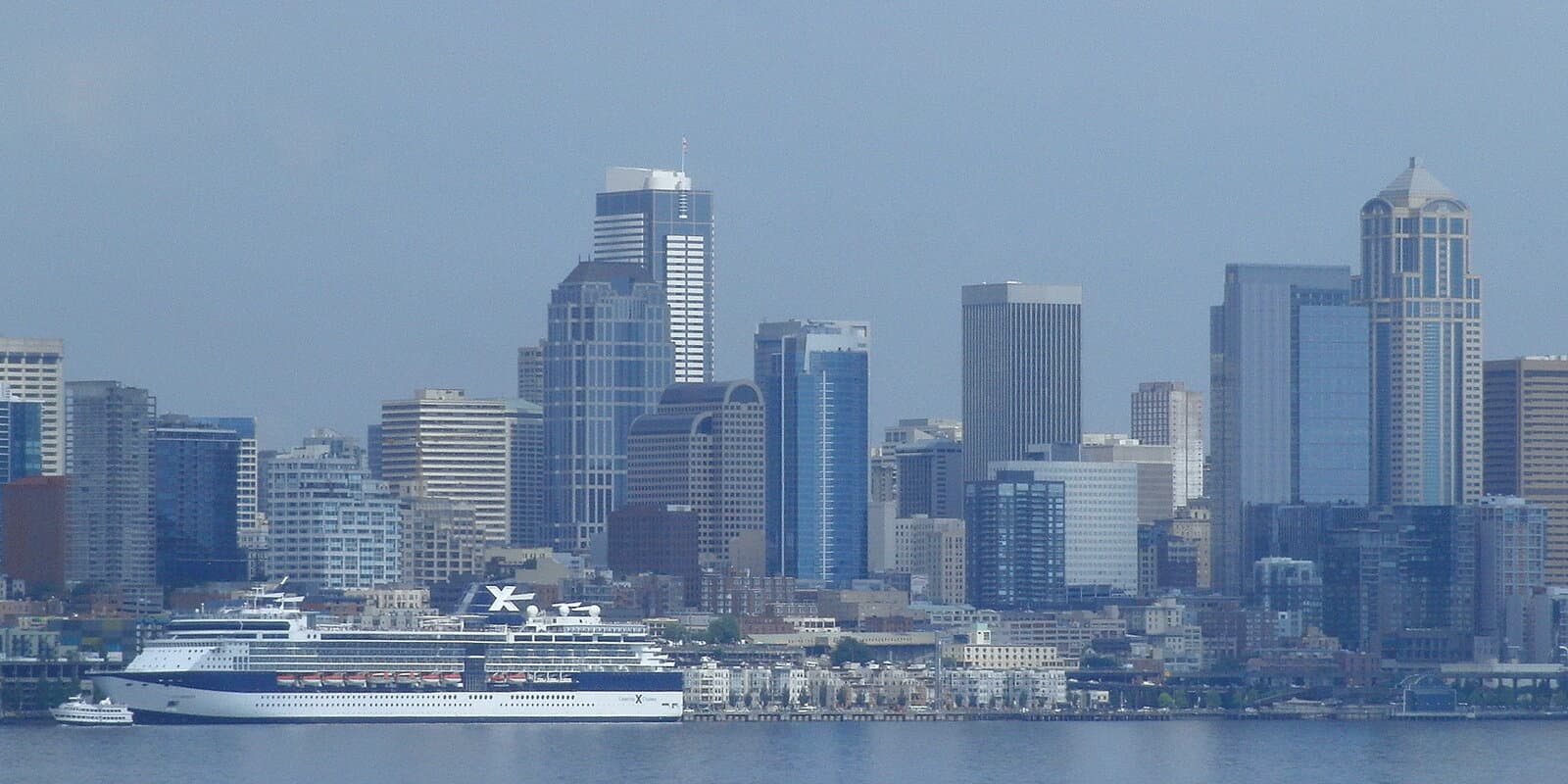 Large cruise ship docked on Elliott Bay with Seattle skyline visible in the background