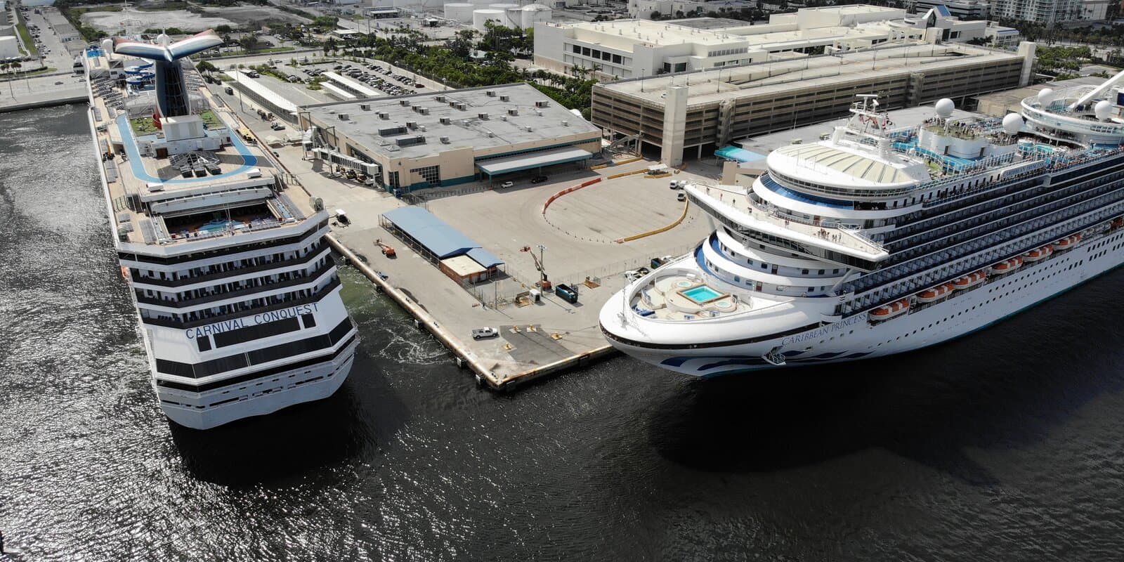 Aerial view of Carnival Conquest and Caribbean Princess docked at Port Everglades with other cruise ships in the harbor