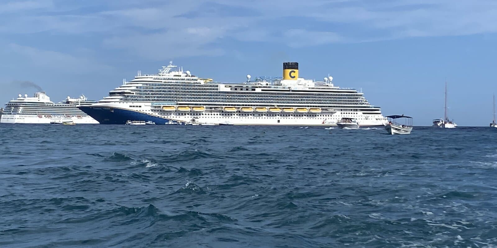 Carnival Firenze and Oceania Vista anchored off Cabo San Lucas, Mexico, on a sunny day, seen from the water
