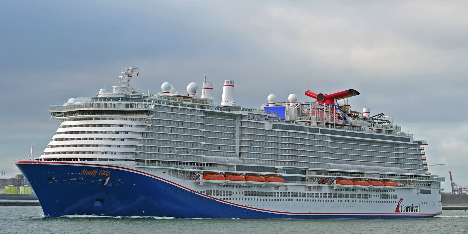 Carnival Mardi Gras cruise ship in profile on open water with red, white, and blue whale-tail funnel and Carnival hull branding