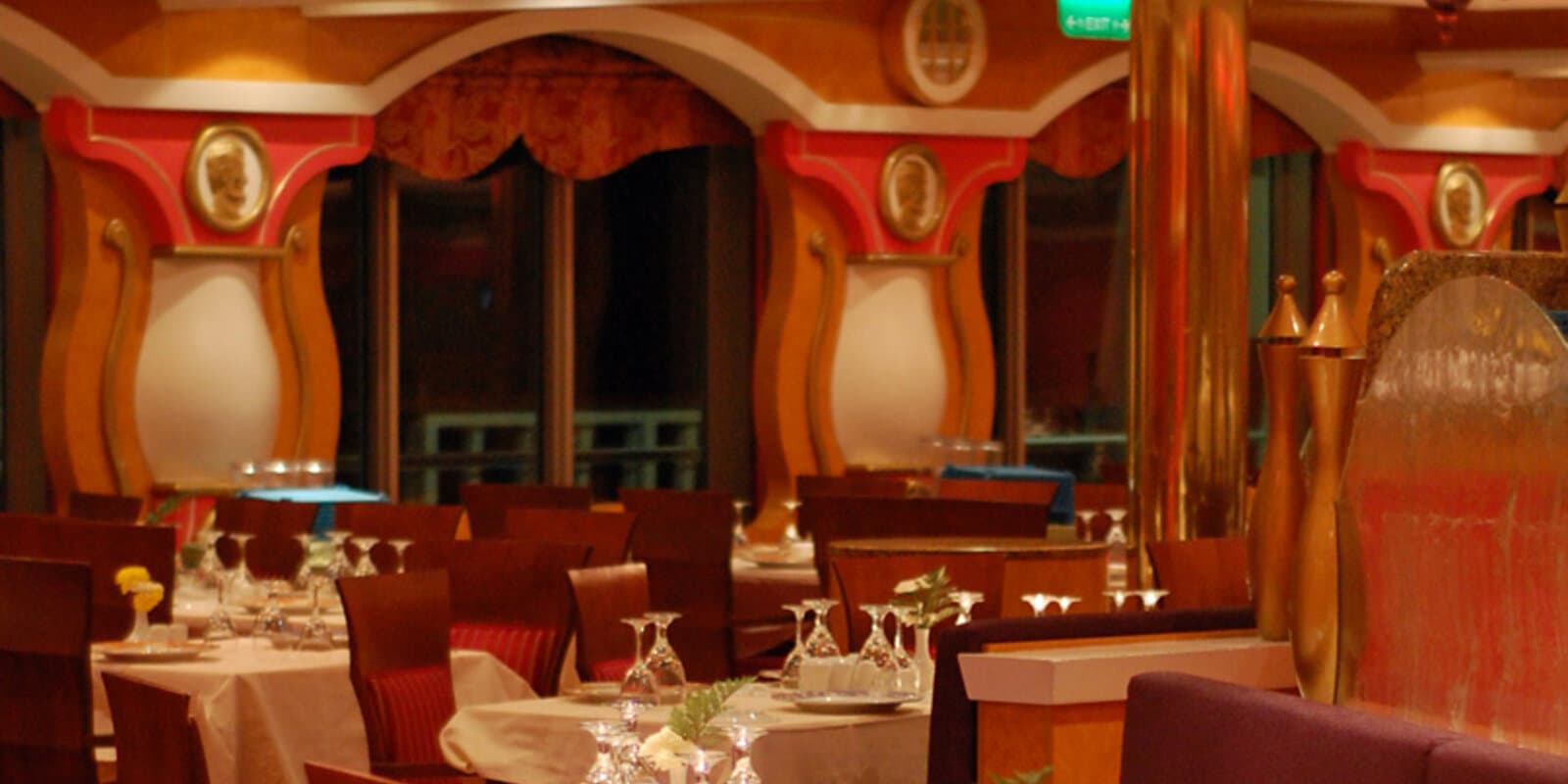 Cruise ship dining room interior with white tablecloths, place settings, and warm lighting