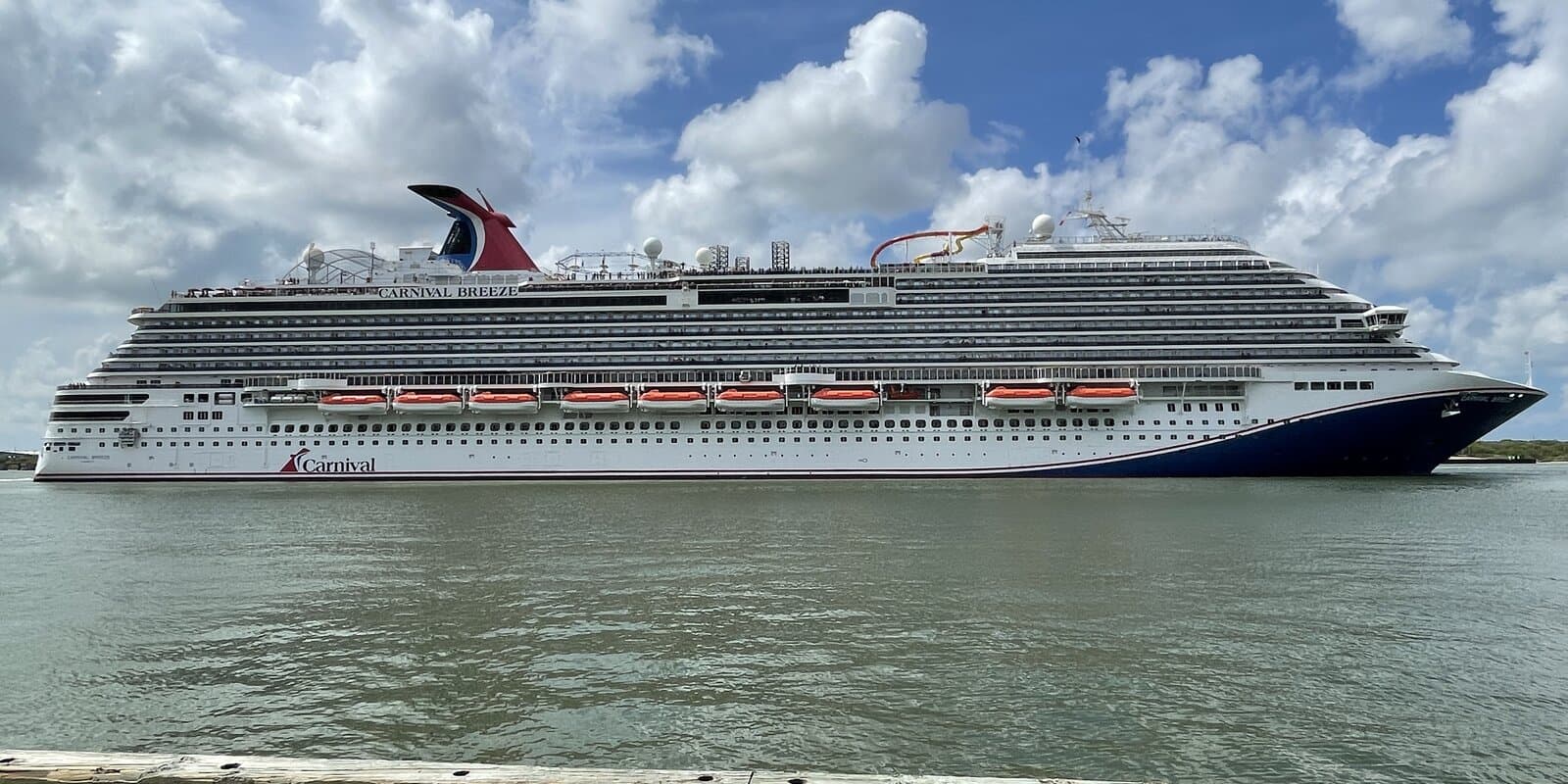 Carnival Breeze cruise ship departing the Port of Galveston on calm water under a partly cloudy sky