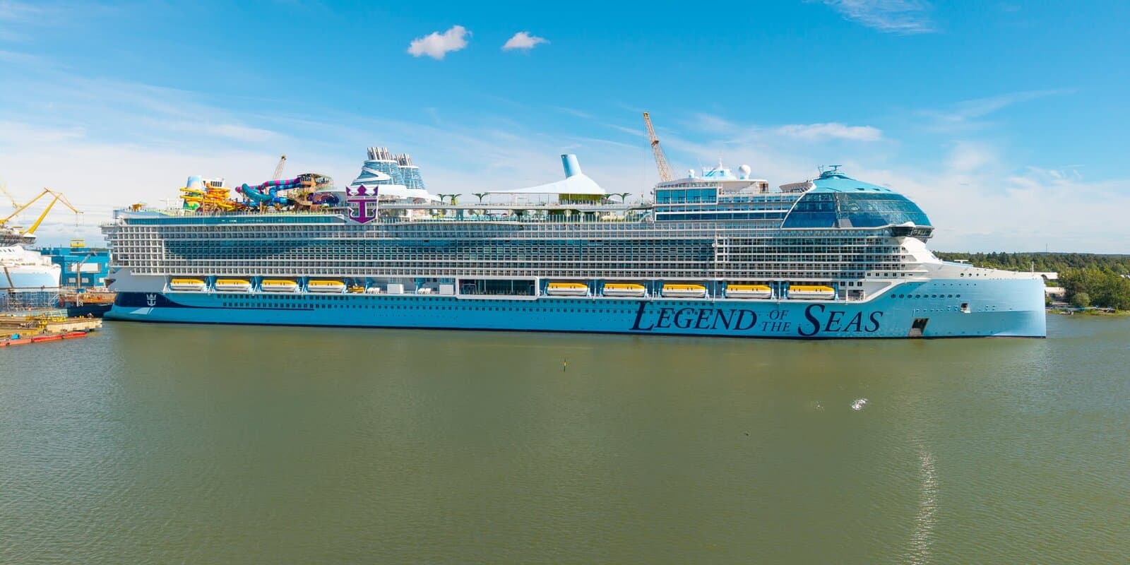 Legend of the Seas at Meyer Turku shipyard in Finland, with shipyard cranes behind the Icon-class hull and the ship name on the bow