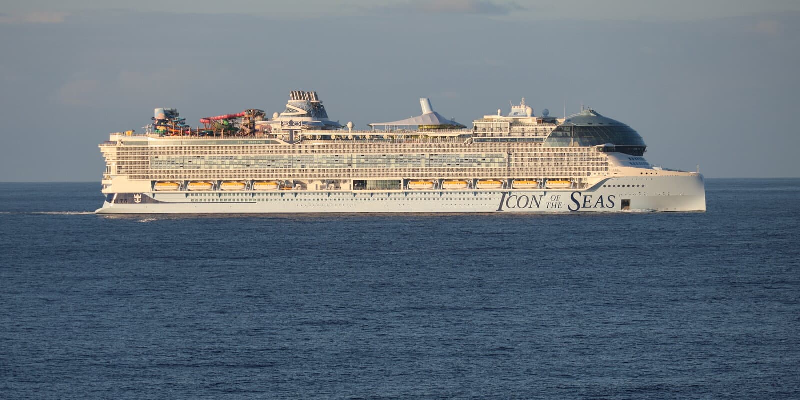 Icon of the Seas underway at sea, an Icon-class sister ship to Legend of the Seas, with AquaDome glass dome, pool decks, and water slides visible in profile