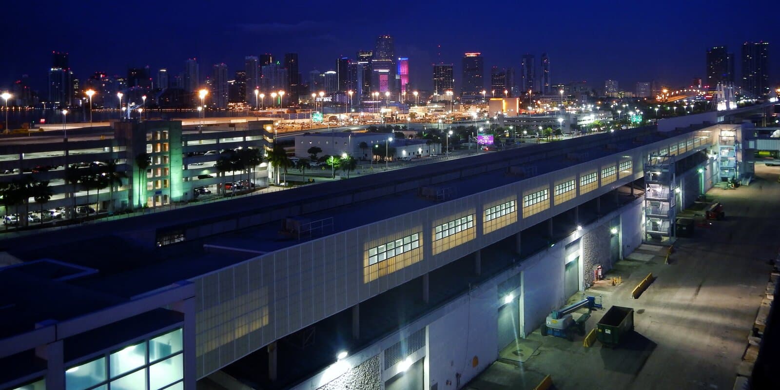 PortMiami cruise terminals on Dodge Island at night with downtown Miami skyline across Biscayne Bay