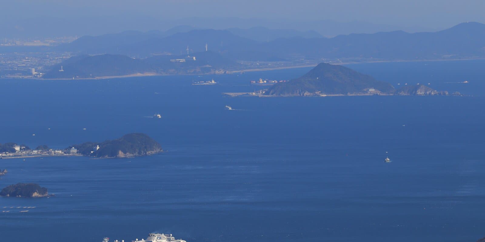 Diamond Princess cruise ship in a blue coastal bay with forested islands and distant mountains, Japan