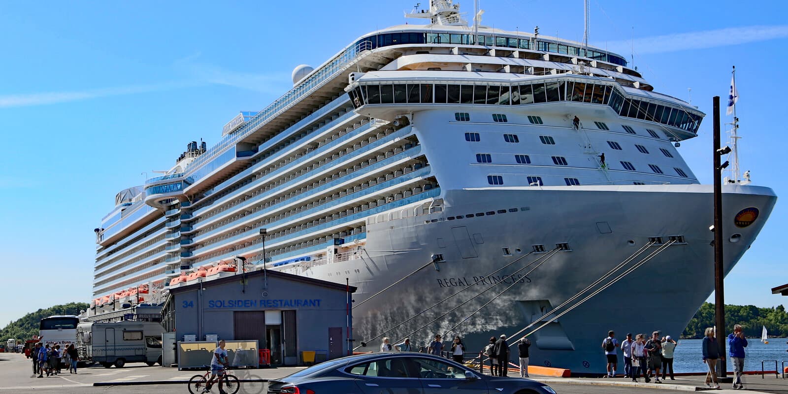 Regal Princess cruise ship at a pier with Princess Cruises branding on the bow and glass-enclosed SeaWalk visible on the upper decks