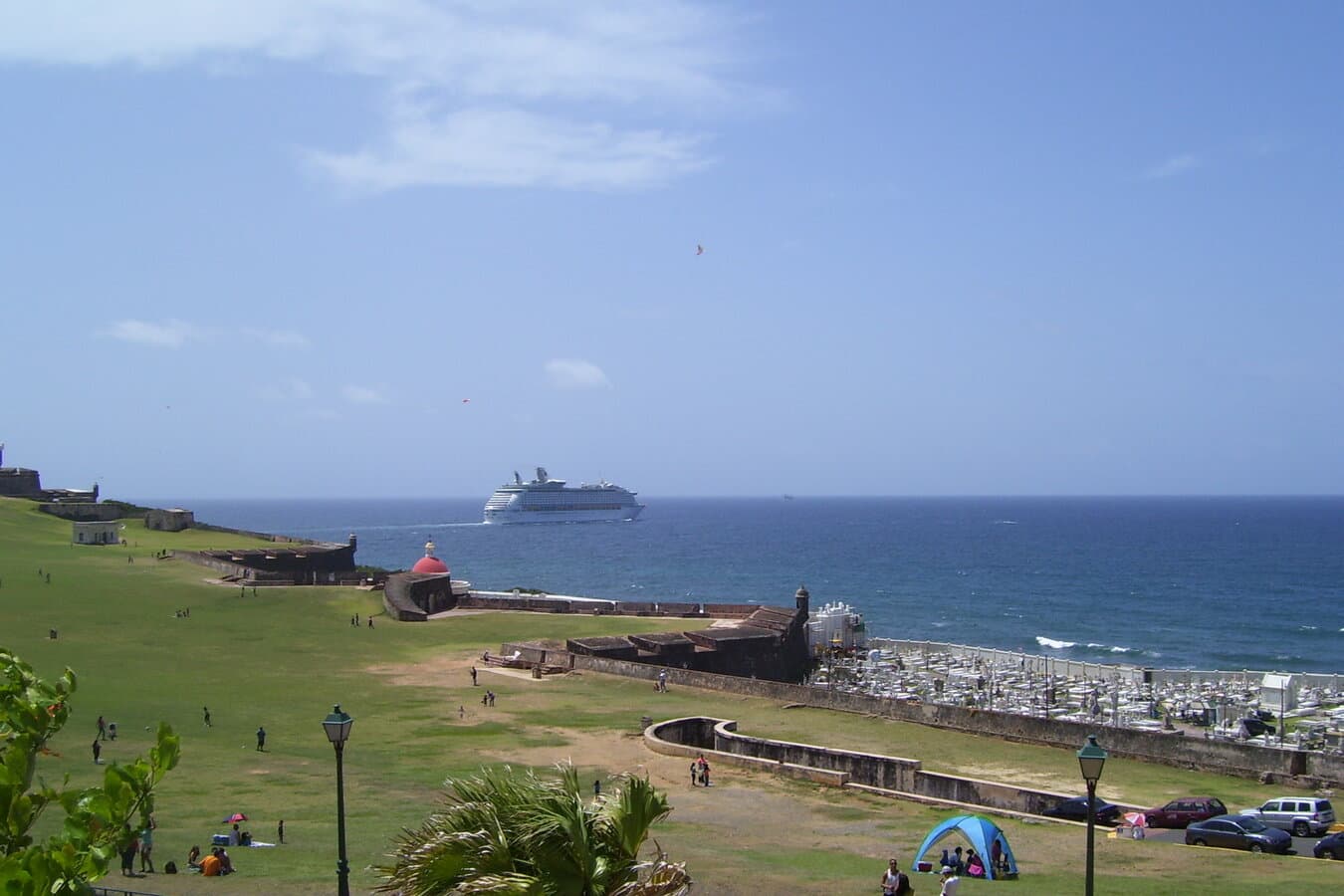 A cruise ship sails past El Morro and the Old San Juan waterfront under a blue Caribbean sky
