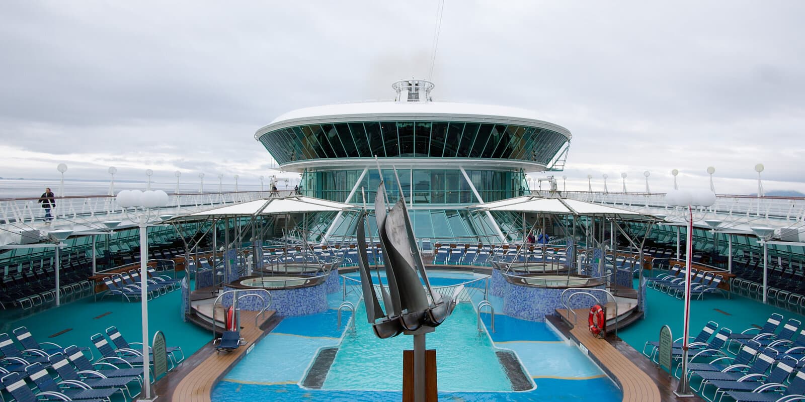 Looking aft over the pool deck of the cruise ship Rhapsody of the Seas with calm open ocean and blue sky beyond the stern