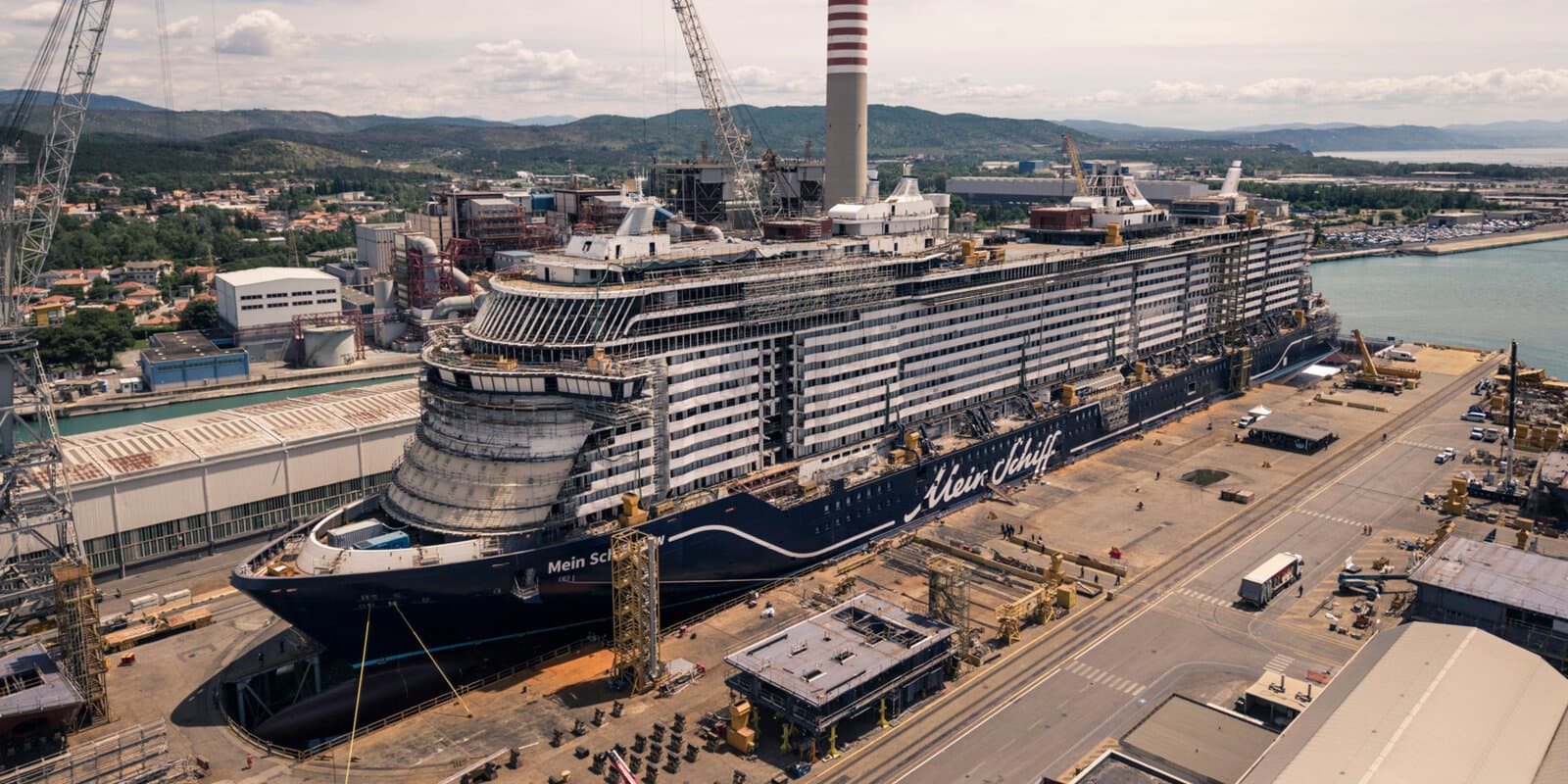 Mein Schiff Flow under construction at the Fincantieri shipyard, with the ship name visible on the navy hull