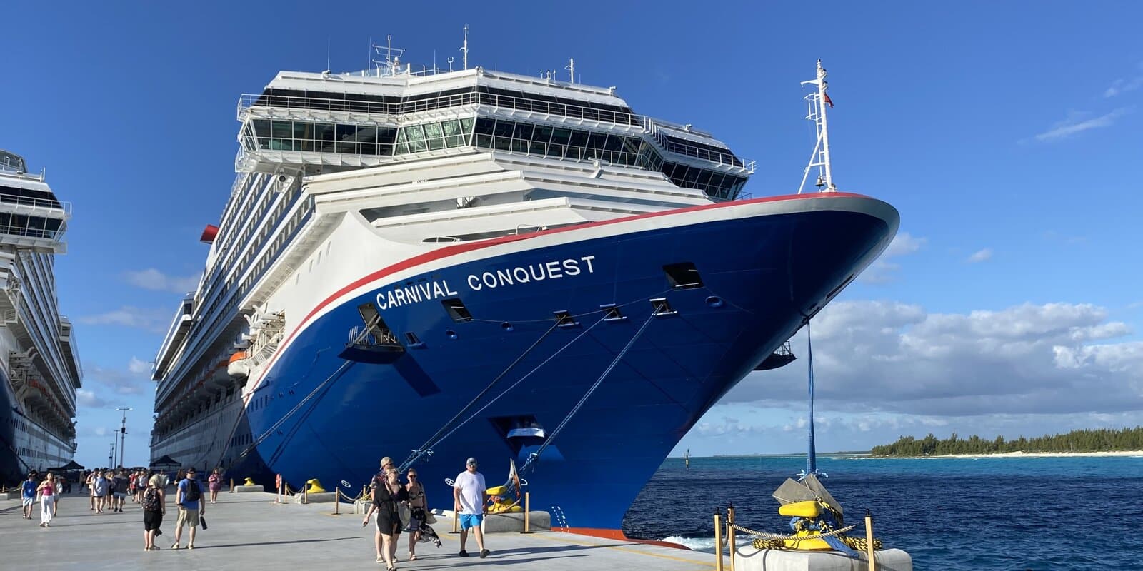 Carnival Conquest bow docked at a Bahamas pier with turquoise water beyond