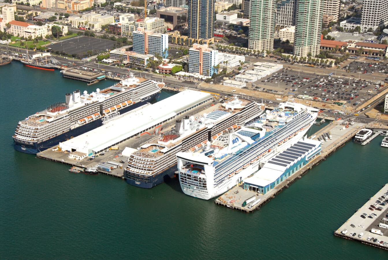 Aerial view of three cruise ships docked at the Port of San Diego Embarcadero terminals with downtown high-rises behind the piers