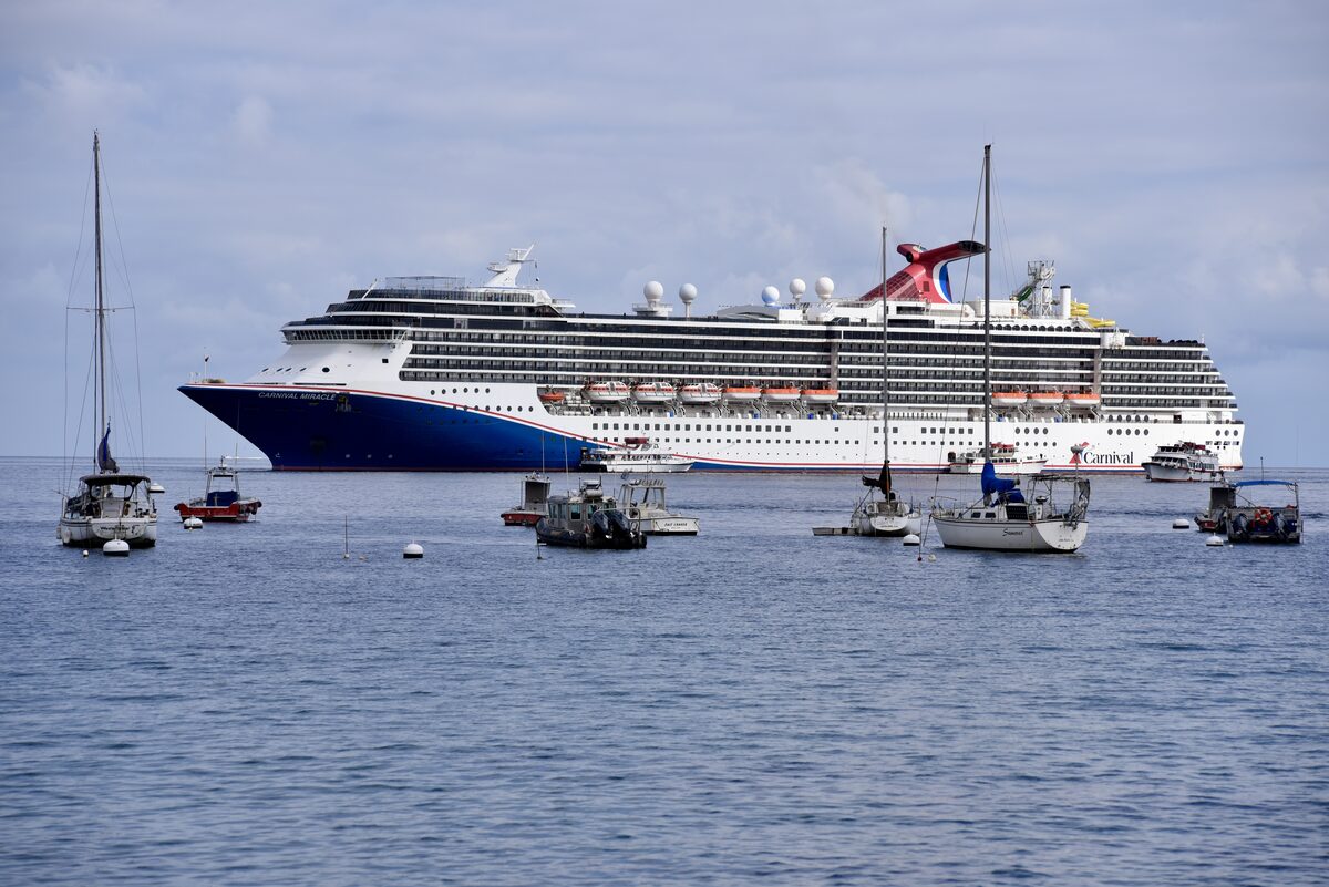 Carnival Miracle cruise ship at anchor with smaller boats in the foreground