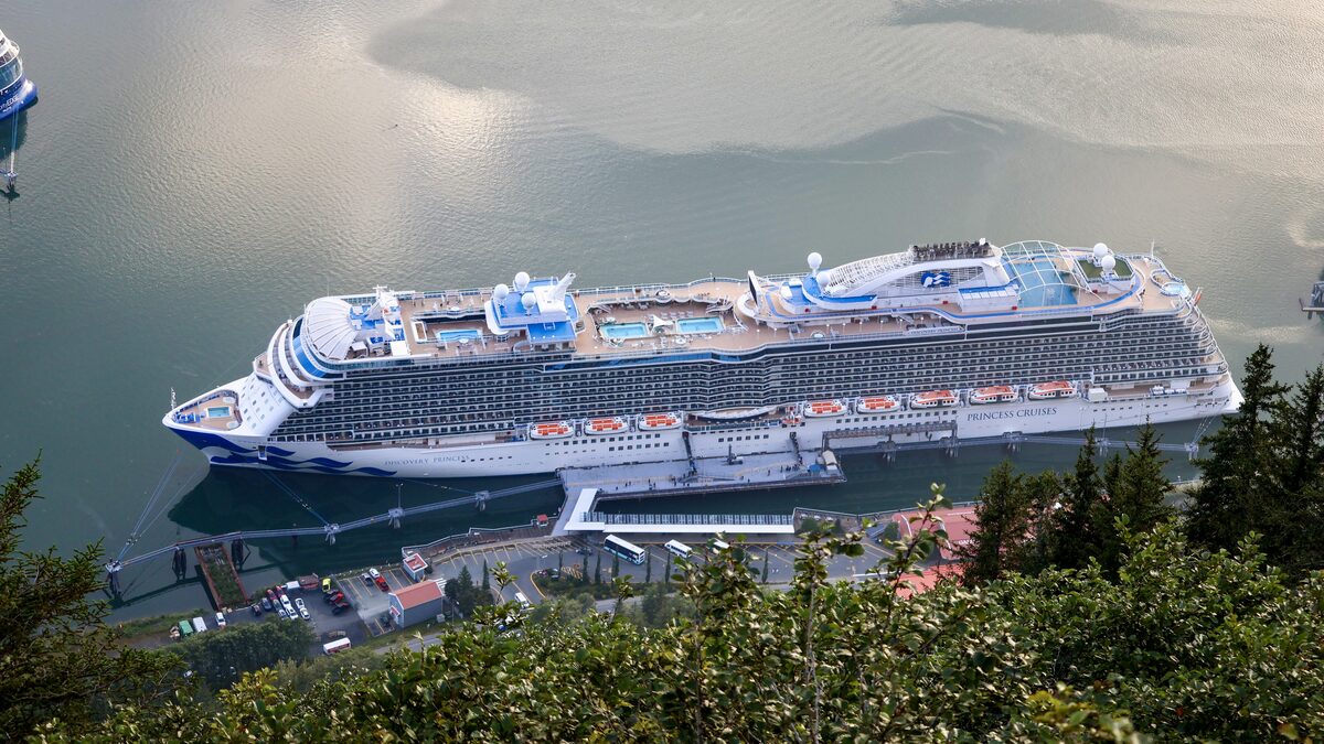 Discovery Princess cruise ship docked in Juneau harbor with forested hills behind the waterfront