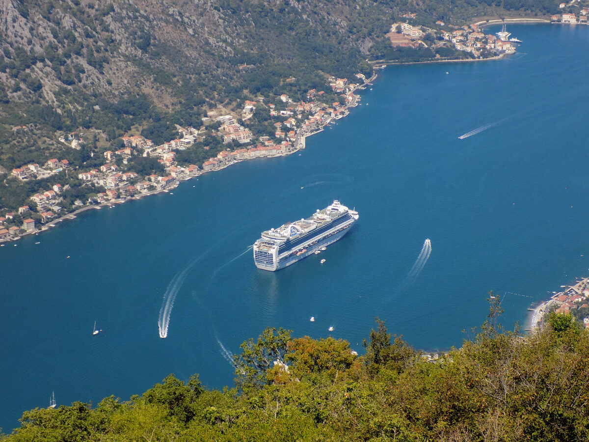 Cruise ship in Montenegro's Bay of Kotor with steep mountains along the shoreline