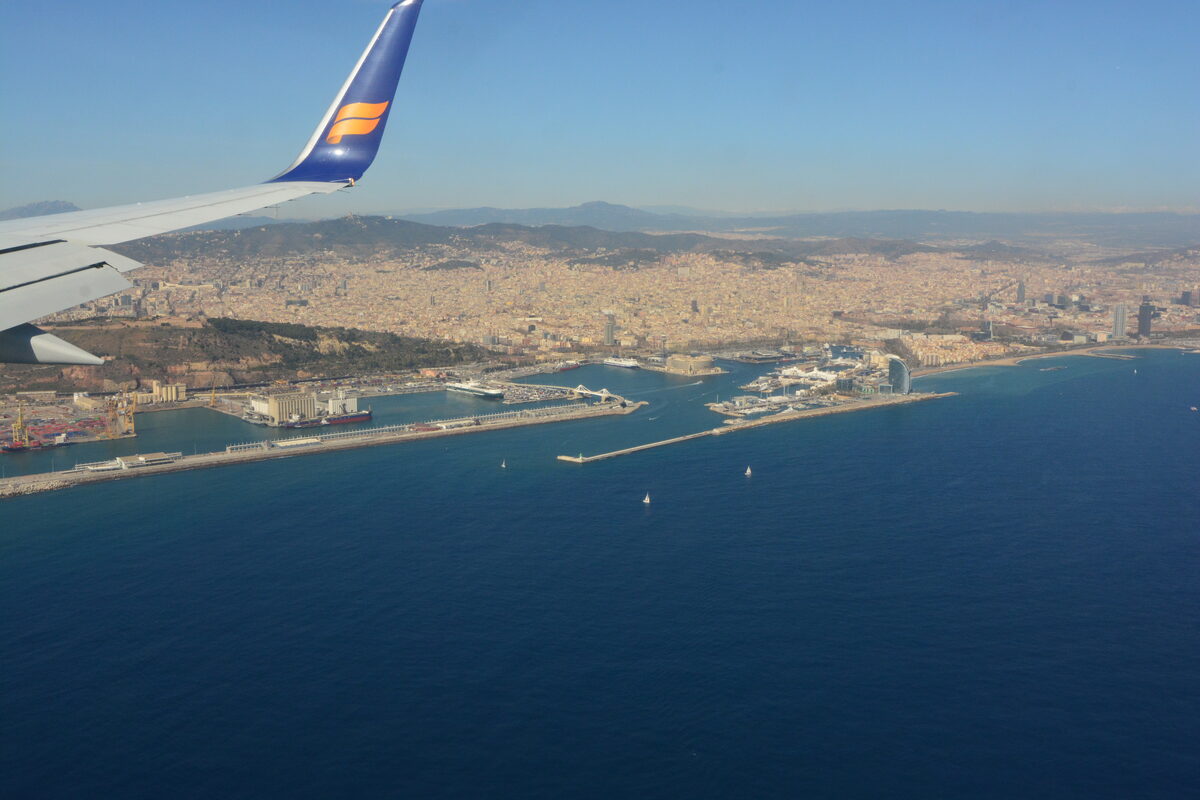 Aerial view of Barcelona's cruise terminals and harbor from over the Mediterranean, with Montjuïc hill and the city skyline inland