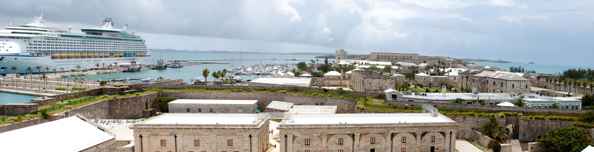 Panoramic view of Royal Naval Dockyard in Bermuda with a cruise ship docked at Kings Wharf and historic stone fort buildings