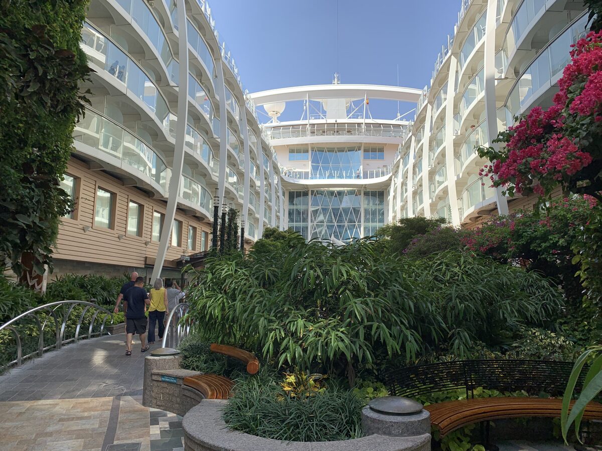 Open-air Central Park neighborhood on Oasis of the Seas, an Oasis-class sister ship to Symphony, with trees, stone paths, and inward-facing balcony cabins