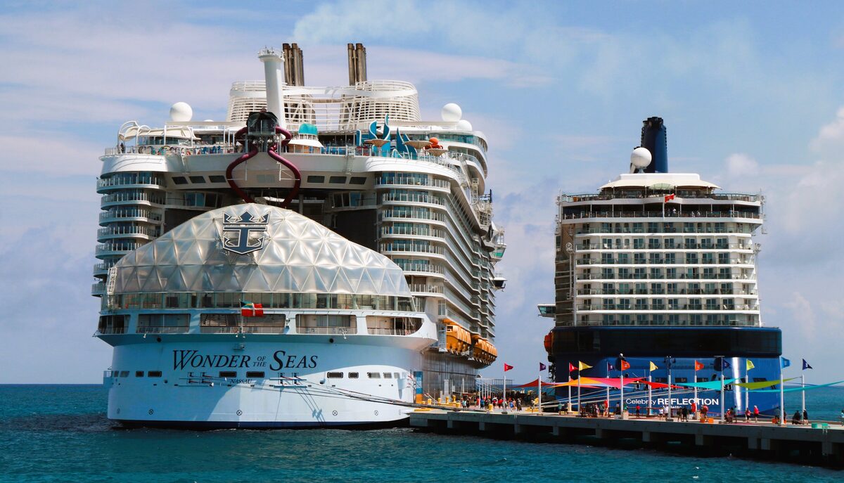 Wonder of the Seas and Celebrity Reflection docked at Perfect Day at CocoCay in the Bahamas with passengers on the pier and turquoise water