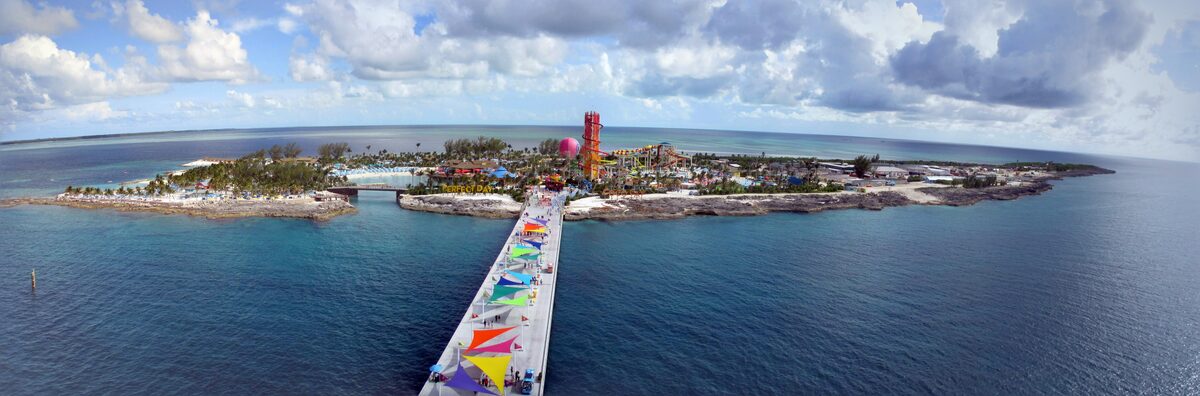 Aerial panorama of Perfect Day at CocoCay in the Bahamas showing the pier, beaches, waterpark towers, and turquoise Caribbean water