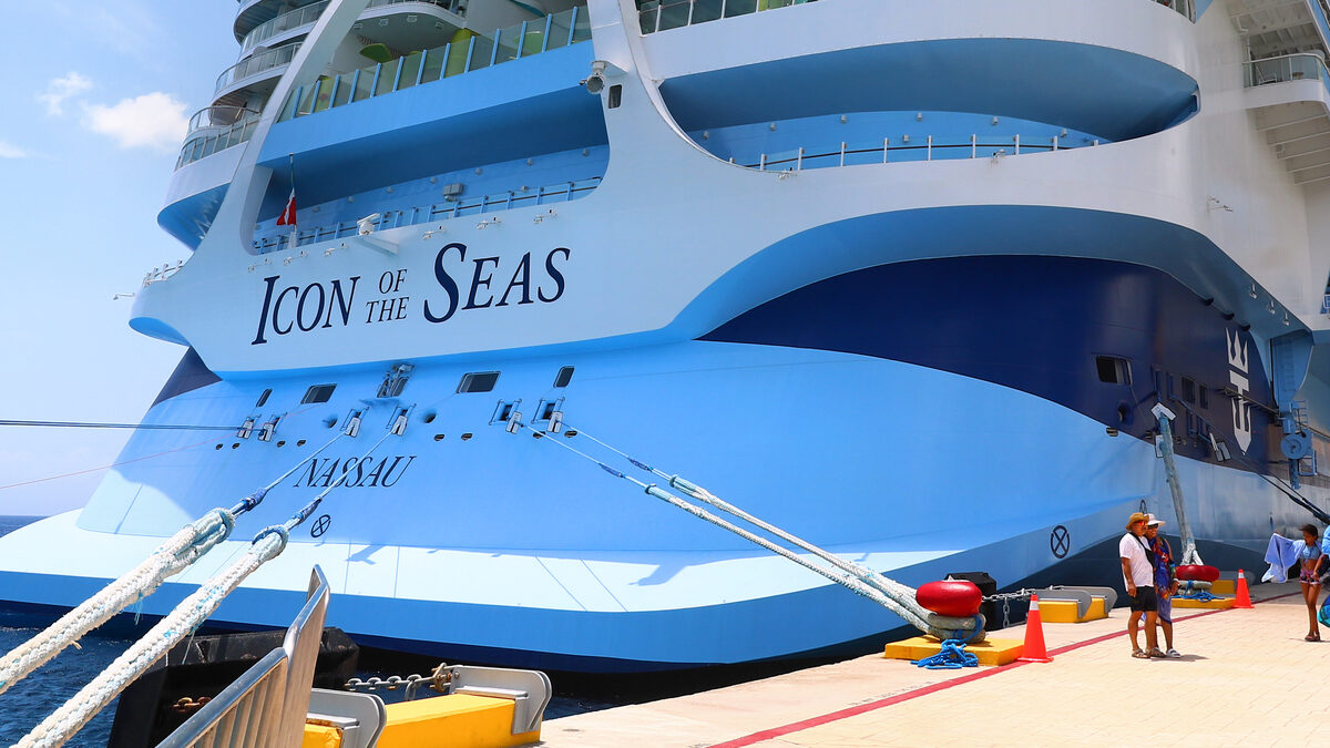 Stern of Icon of the Seas docked at a cruise terminal, showing stacked balcony decks and the scale of Icon-class neighborhood layout