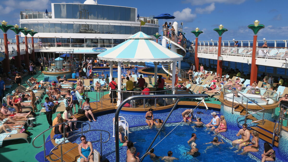 Passengers on the pool deck of a Norwegian Cruise Line ship on a sunny sea day