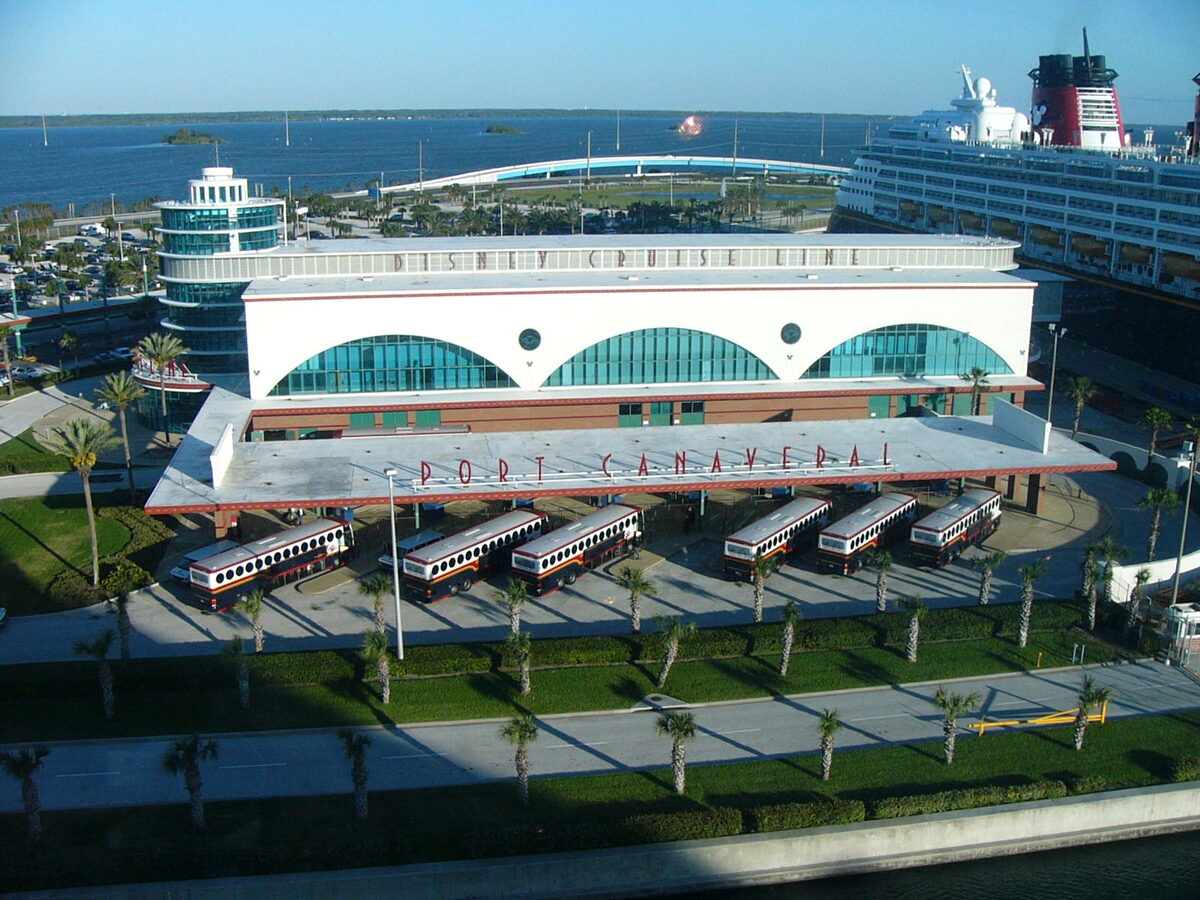 Port Canaveral cruise terminal with a docked ship, parking lots, and shuttle buses at the pier