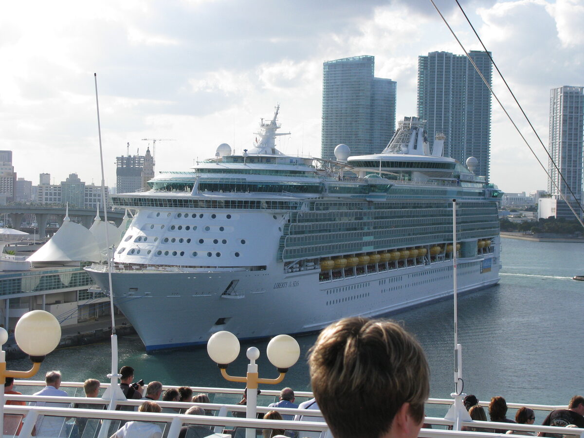Liberty of the Seas docked at a PortMiami terminal with the Miami skyline behind the ship