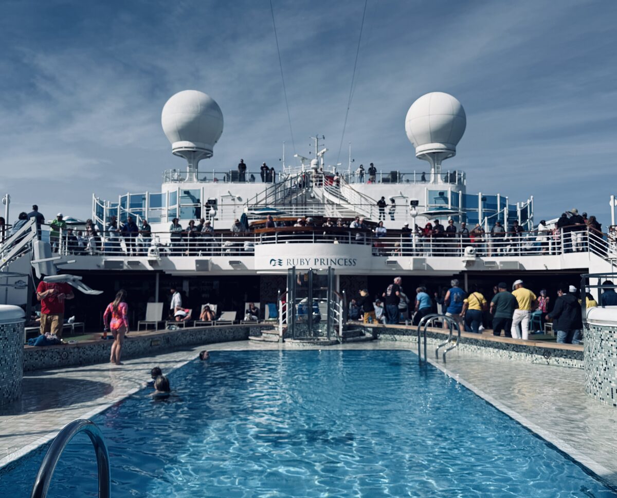 Ruby Princess Lido deck pool area with passengers gathered on the upper decks on a sunny day at sea