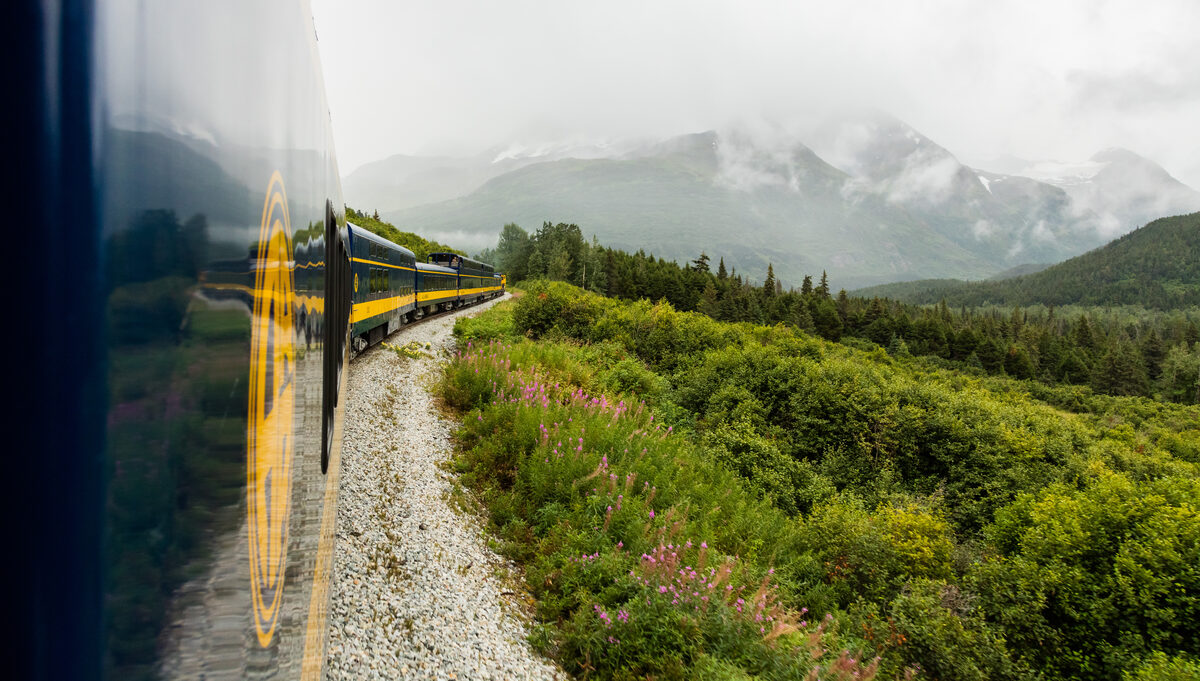 Alaska Railroad passenger train on tracks through forested Kenai Peninsula mountains on the Seward–Anchorage corridor