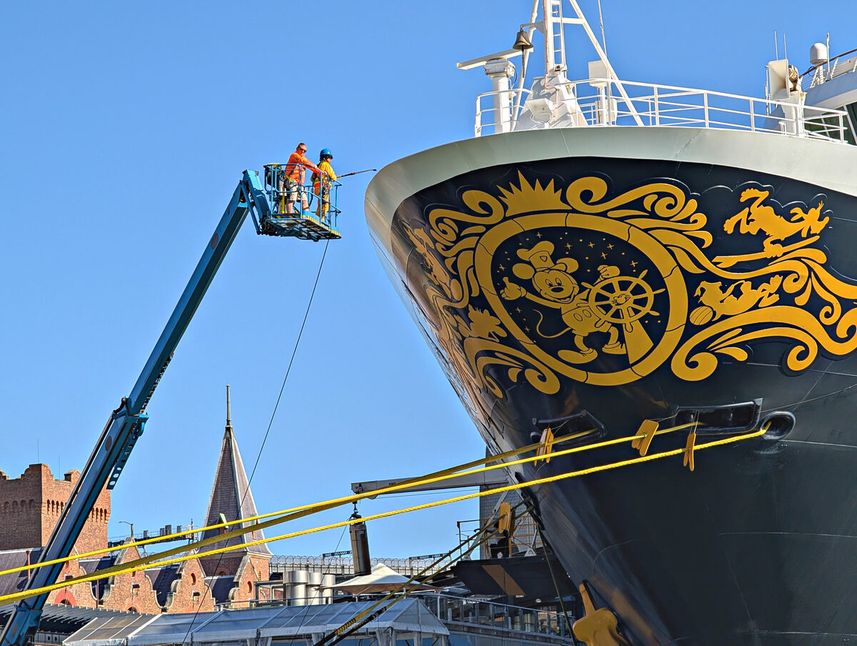 Bow of Disney Wonder showing the navy hull and golden Mickey Steamboat Willie scrollwork while docked in Sydney